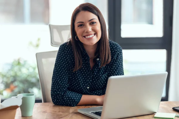 Modern Bir Ofiste Kameraya Bakarken Bilgisayarla Çalışan Gülümseyen Bir Kadını — Stok fotoğraf