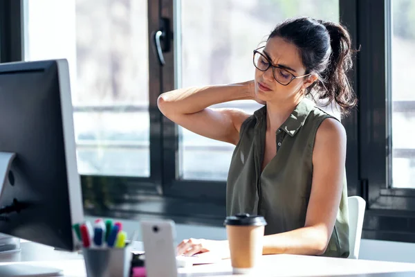 オフィスでコンピュータを操作しながら不快な顔をしながら首の痛みを持つ疲れビジネス女性のショット — ストック写真