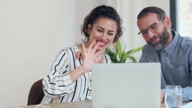 Modern başlangıçta bilgisayarla video görüşmesi yaparken el sallayan iş adamı videosu.