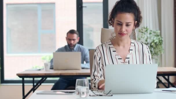 現代のスタートアップオフィスでデスクに座っている間にコンピュータで働く魅力的な若いビジネス女性のビデオ — ストック動画