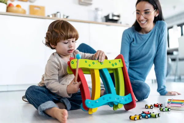 Evdeki oturma odasında oğluyla yerde oynayan güzel bir annenin fotoğrafı..