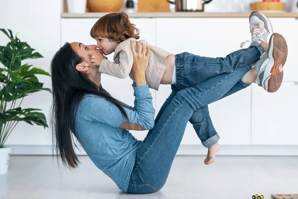 Genç ve güzel annenin evdeki oturma odasında oğluyla yerde oynayıp eğlenmesi..