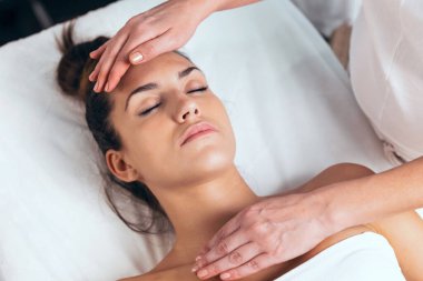 Sağlık merkezinde Reiki tedavisi gören güzel bir genç kadın fotoğrafı.