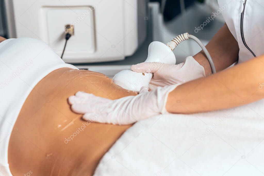 Shot of cosmetologist makes the procedure an ultrasonic cleaning of skin of a beautiful young woman on the spa center.