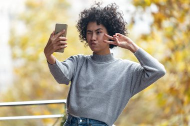 Evdeki balkonda dikilirken akıllı telefonuyla fotoğraf çeken güzel bir kadın..