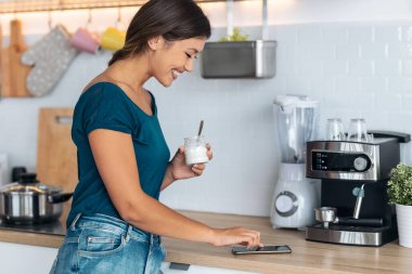 Evde yoğurt yerken güzel bir kadının cep telefonuyla mesaj göndermesi..