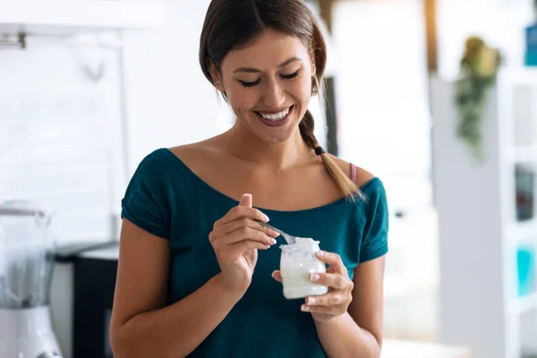 Tiros Bela Mulher Feliz Comendo Iogurte Enquanto Sorri Pensando Suas — Fotografia de Stock