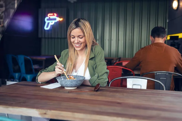 アジア料理店で箸でラーメンを食べる面白い女性のショット — ストック写真