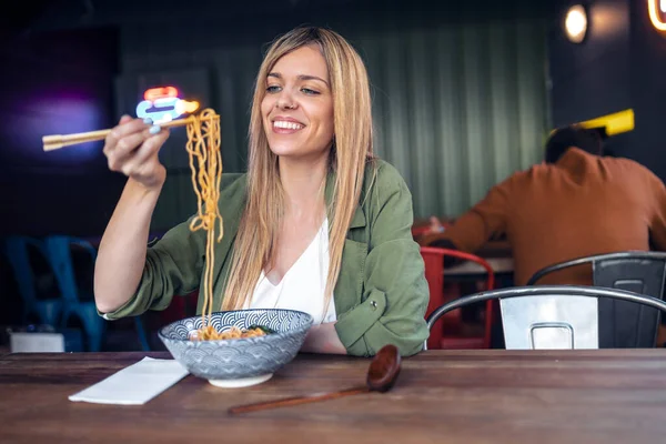 アジア料理店で箸でラーメンを食べる面白い女性のショット — ストック写真