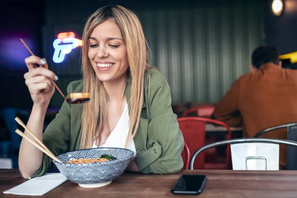 アジア料理店で箸でラーメンを食べる面白い女性のショット — ストック写真