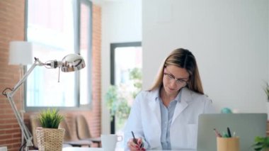 Konsültasyonda bilgisayarla çalışan olgun, konsantre, çekici bir kadın doktorun videosu..