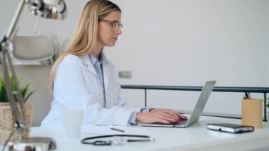 Konsültasyonda bilgisayarla çalışan olgun, konsantre, çekici bir kadın doktorun videosu..