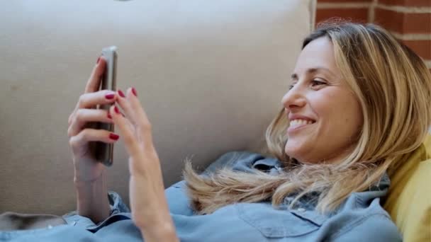 Видео Довольно Зрелой Женщины Помощью Мобильного Телефона Расслабляясь Сидя Диване — стоковое видео