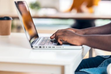 Birlikte çalıştığı bir yerde dizüstü bilgisayarda yazan iş adamının ellerini kapat..