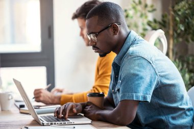 Modern başlangıç ofisinde bilgisayarla çalışan iki konsantre grafik tasarımcısının çekimi.