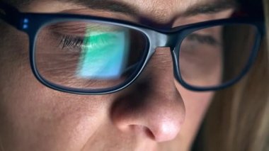 Yetişkin bir kadının evdeki oturma odasında kanepede otururken dijital tablette kitap okuduğu bir video..