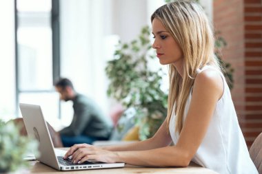 Kocası evdeki kanepede dinlenirken güzel bir kadının bilgisayar kullanması..