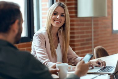 İş yerinde konuşurken dizüstü bilgisayarla çalışan akıllı iş adamlarının fotoğrafı..