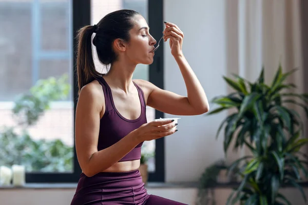 Evde Fitness Topunun Üzerinde Otururken Yoğurt Yiyen Genç Bir Kadın — Stok fotoğraf