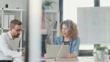 Birlikte çalışma alanındaki çalışmaların sunumu için bilgisayarın etrafında duran başarılı iş çoklu yaş ekibinin videosu.