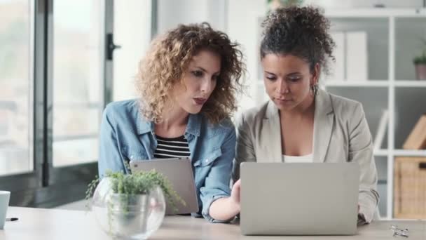 現代のスタートアップオフィスでデジタルタブレットやラップトップと協力している2人のビジネス女性のビデオ — ストック動画
