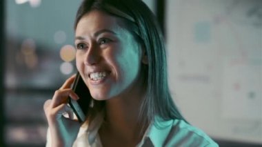 Modern bir ofiste çalışırken akıllı telefonuyla konuşan güzel iş kadınının videosu..