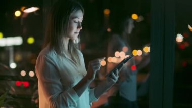 Zeki, güzel bir iş kadınının, gece ofiste dijital tabletini çiğnerken mola verdiği bir video..