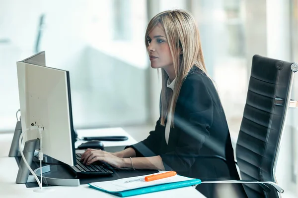 現代のスタートアップオフィスでデスクに座っている間 コンピュータで働く美しい若いビジネス女性のショット — ストック写真