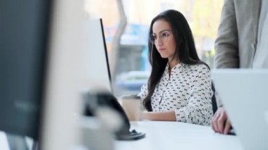 Ofiste bilgisayarla çalışırken cep telefonuyla konuşan çekici bir iş kadını videosu..
