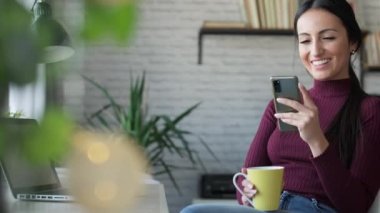 Güzellik sektörü kadınının evde çalışırken ve kahve içerken cep telefonuyla mesaj gönderdiği video..