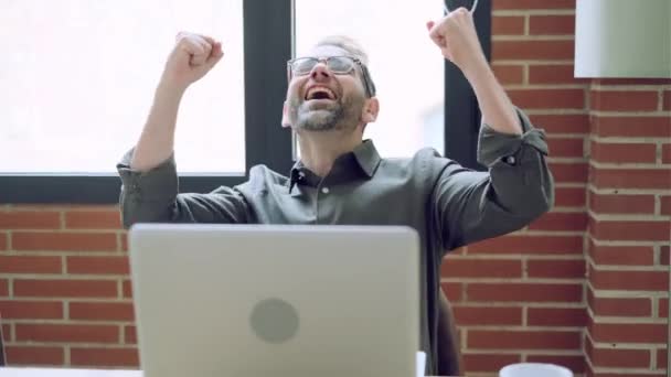 Wideo Odnoszącym Sukcesy Dojrzałym Biznesmenem Świętującym Coś Podczas Pracy Laptopem — Wideo stockowe