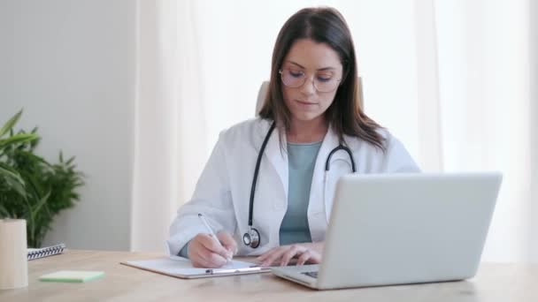 Video Atractiva Doctora Que Trabaja Con Computadora Mientras Escribe Notas — Vídeos de Stock