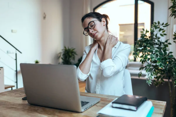 オフィスでノートパソコンを操作している間に不快な顔をして首の痛みを持つ疲れビジネス女性のショット — ストック写真