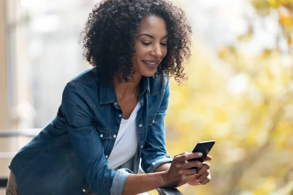 Foto Mujer Alegre Usando Teléfono Inteligente Mientras Envía Mensajes Pie — Foto de Stock