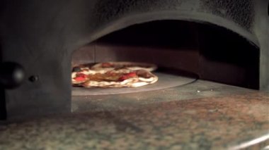 Pizza kaseti, restoran mutfağında kürekle odun ateşindeki pizza fırınında.