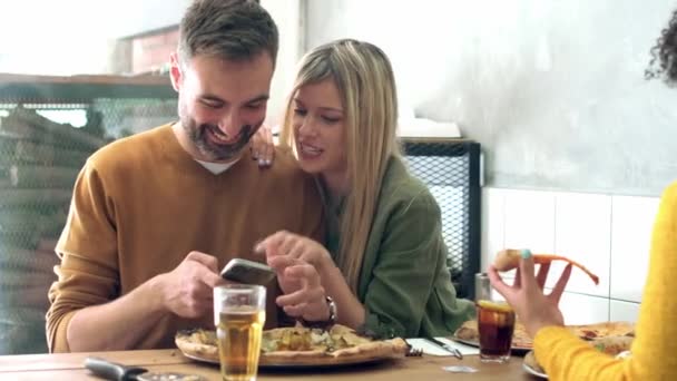 Vídeo Casal Lindo Compartilhando Telefone Inteligente Enquanto Come Pizza Restaurante — Vídeo de Stock