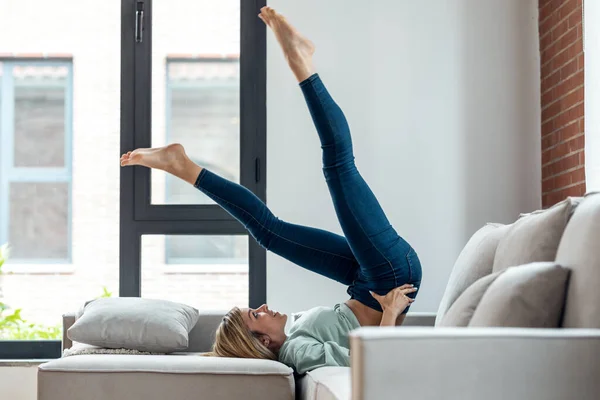 Evdeki Kanepede Dinlenirken Jimnastik Yapan Komik Bir Genç Kadın — Stok fotoğraf