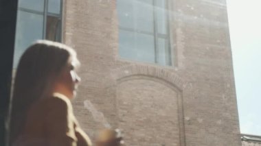 Evdeki pencerenin yanında dikilmiş bir fincan kahve içen güzel genç bir kadının videosu..