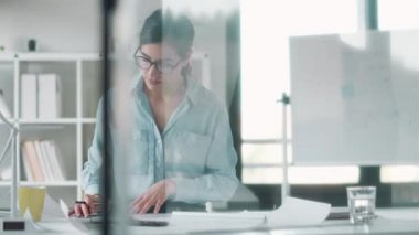 Ofiste notlar alırken tasarım sırasında çalışan konsantre kadın mimarın videosu.