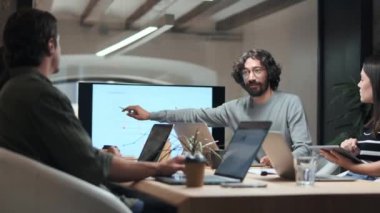 Akıllı iş adamının iş arkadaşlarıyla ortak çalışma yerindeki bilgisayarında istatistikleri olan bir projeyi anlattığı video..