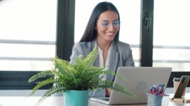 Ofisten dizüstü bilgisayarla video konferansı yaparken kameradan kendine güvenen iş kadınının görüntüsü ve konuşması..