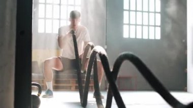 Sporcu fitness antrenmanının videosu. Çapraz formda spor salonunda siyah savaş halatlarıyla..