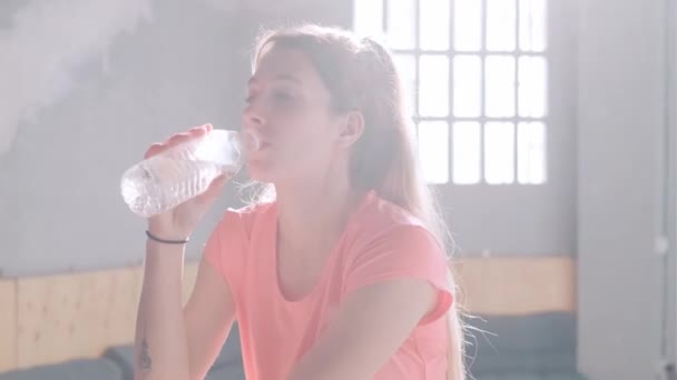 運動選手の女性のビデオは フィットネストレーニング運動後に新鮮なミネラルクリア水を飲むボトルを保持クロスフィットジムで — ストック動画