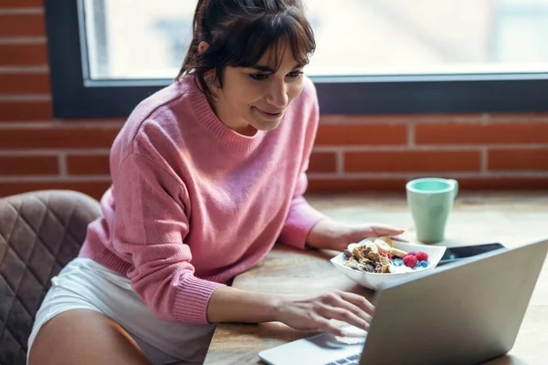 Tiro Bela Jovem Mulher Trabalhando Com Laptop Enquanto Come Iogurte — Fotografia de Stock