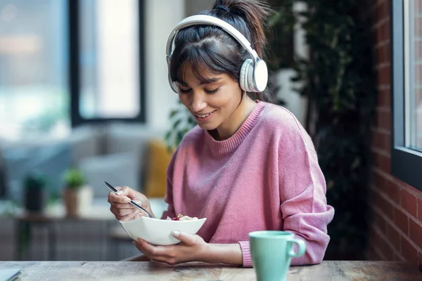 Foto Hermosa Mujer Joven Escuchando Música Con Auriculares Mientras Desayuna — Foto de Stock