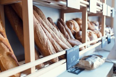Shot of different types of delicious bread loaves placed on the shelf in a pastry shop. 