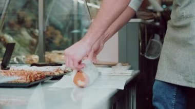Video of cheerfu manl seller giving fresh loaf of bread to smiling woman in the pastry shop.