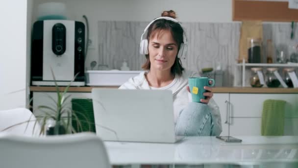 Видео Вдумчивой Зрелой Женщины Смотрящей Свой Ноутбук Держа Чашку Кофе — стоковое видео