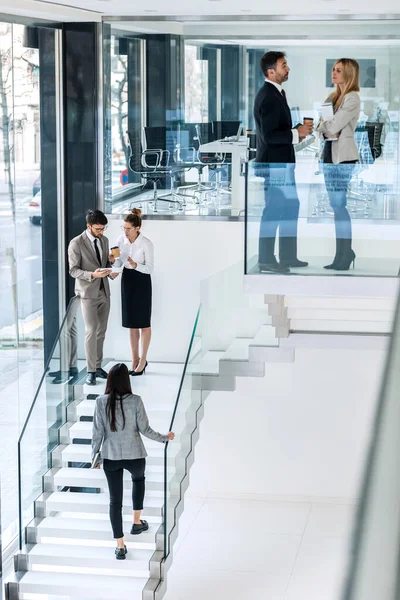 Shot of elegant business people discussing together while standing on the stairs in a modern startup.