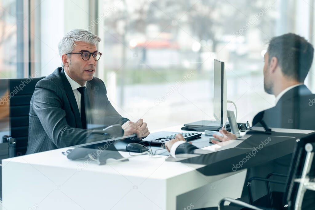 Shot of concentrated mature businessman listening his partner while working in a modern startup.